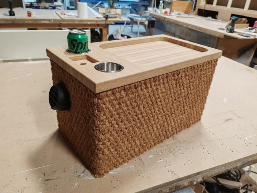 A woven storage box with a wooden lid, featuring a drink holder and a can on top.